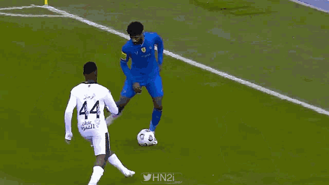 a soccer player with the number 44 on his jersey is trying to get the ball from another player