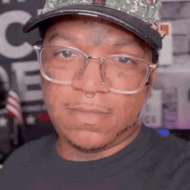 a man wearing glasses and a hat has a tattoo on his forehead that says can