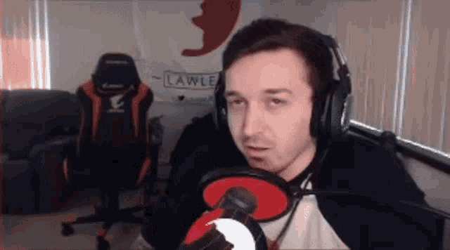 a man wearing headphones is talking into a microphone in front of a chair .