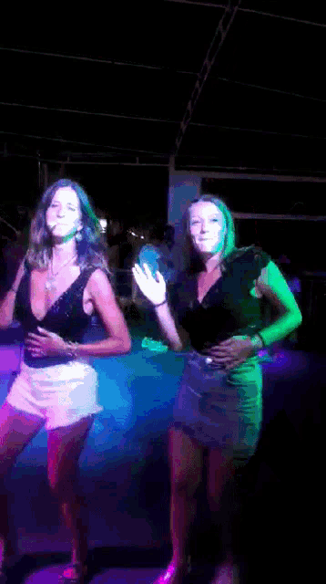 a couple of women are dancing in a dark room