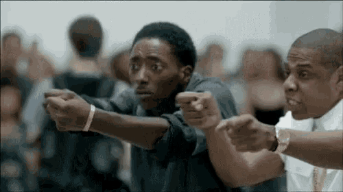 two men are pointing at each other with their hands in a crowd .