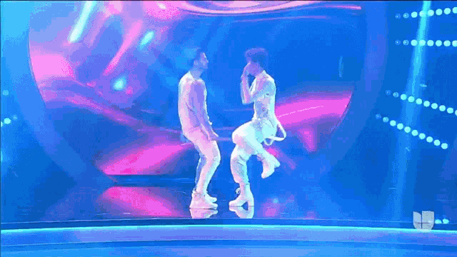 two men are dancing on a stage with the letters nb on the bottom