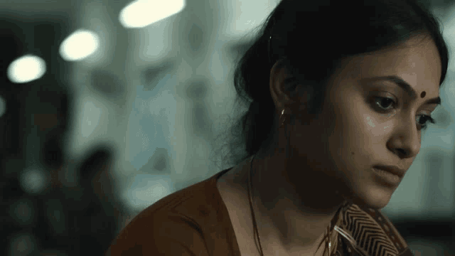 a woman with a bindi on her forehead looks down at something