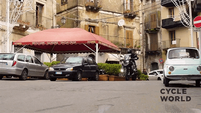 a motorcycle is parked under a red awning that says tavola calda