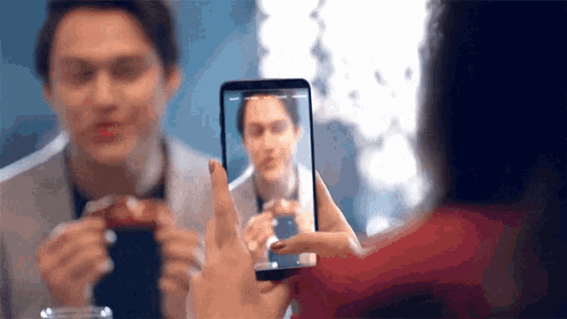 a woman is taking a picture of a man eating a sandwich