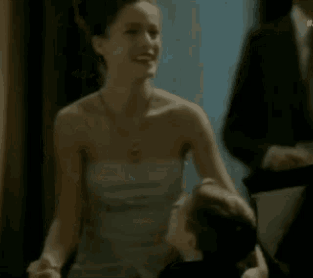 a woman in a strapless dress is laughing while holding a boy .