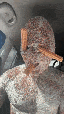 a person is covered in frosting and sprinkles with churros sticking out of his mouth