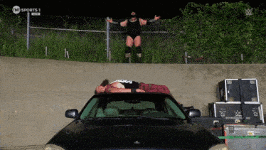 a wrestler laying on top of a car with tnt sports 1 on the bottom right