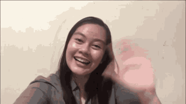 a woman is taking a selfie and waving at the camera .