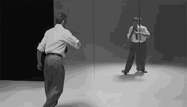 a man is dancing in front of a mirror