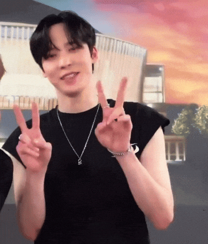 a man wearing a black shirt and a necklace is giving the peace sign