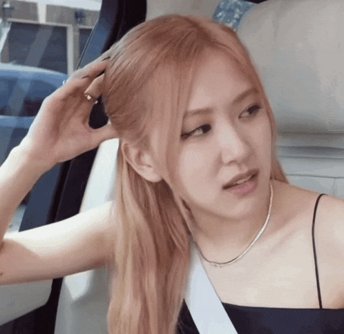 a woman wearing a black top and a necklace is sitting in the back seat of a car