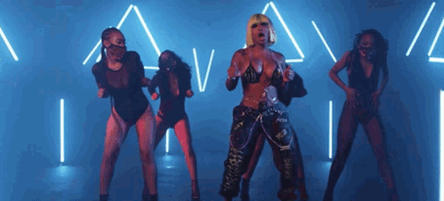 a woman in a bikini is surrounded by dancers