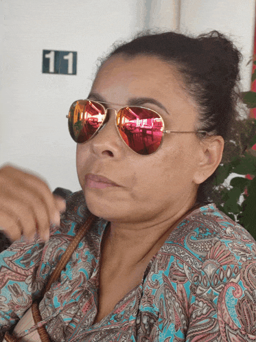 a woman wearing sunglasses is sitting in front of a sign that says 11