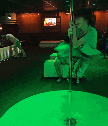 a woman stands on a pole in a green room