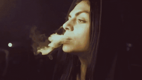 a woman is smoking a cigarette in a dark room at night .