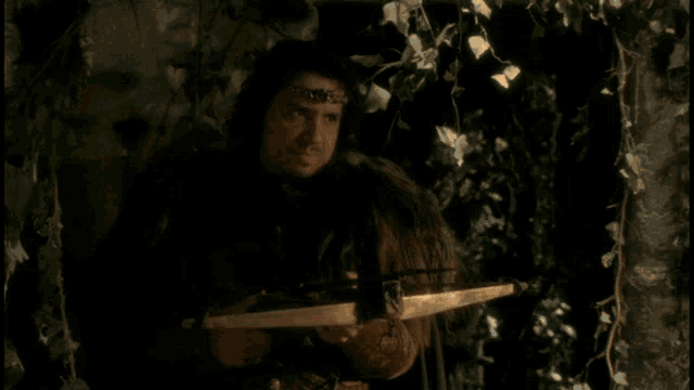 a man with a crown on his head holds a bow and arrow