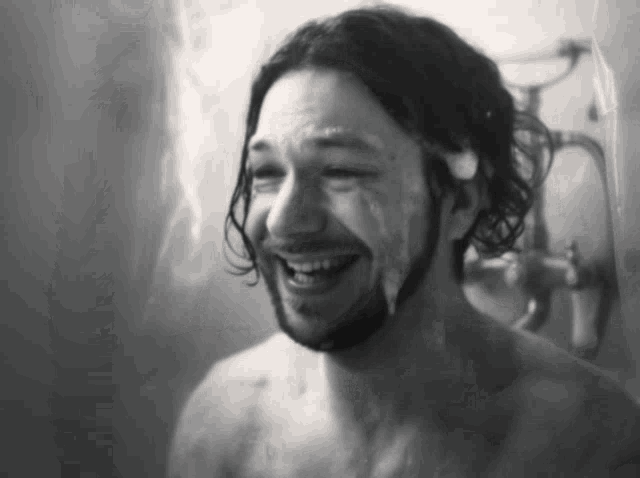 a black and white photo of a man taking a shower with soap on his face