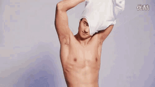 a shirtless man is standing in front of a white background with his arm outstretched .