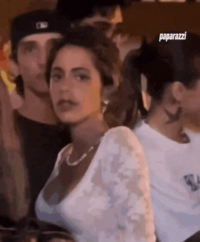 a woman is sitting in a crowd of people and looking at the camera .