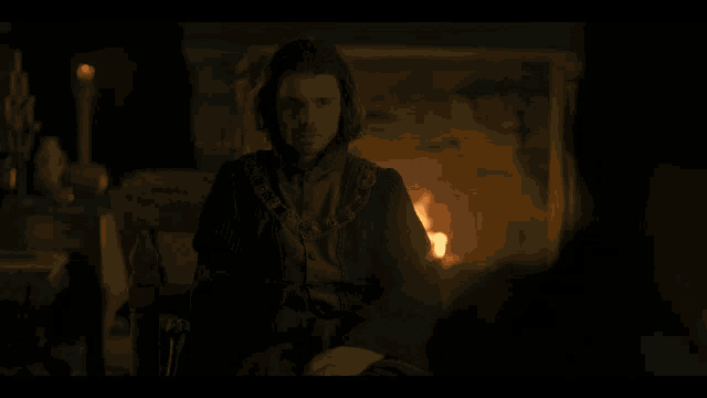 a man sitting in front of a fireplace with a candle