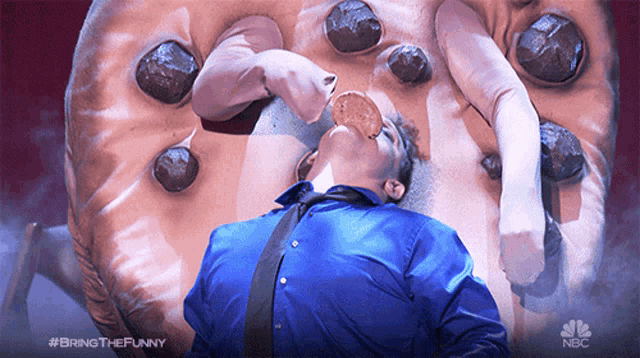 a man is eating a cookie in front of a giant cookie that says bring the funny on it