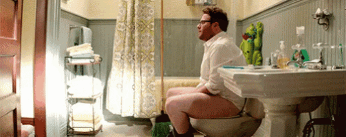 a man is sitting on a toilet in a bathroom without pants .