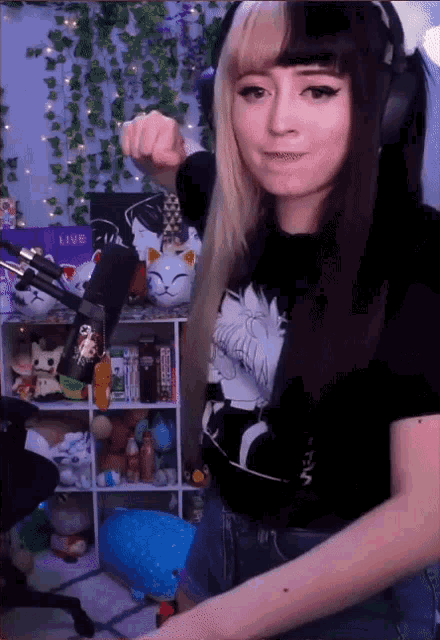 a girl wearing headphones and a shirt that says ' sfw ' on it stands in front of a microphone