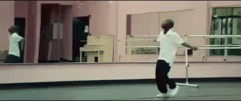 a man is dancing in a dance studio in front of a mirror .