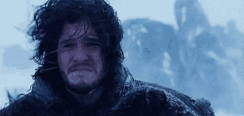 a man with long hair and a beard is standing in the snow with his eyes closed .