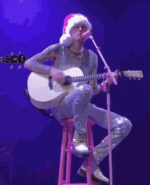 a man wearing a santa hat plays a guitar