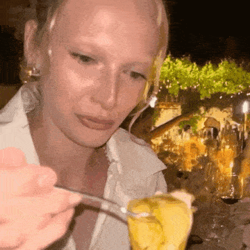 a woman in a white shirt is eating a dessert with a fork .