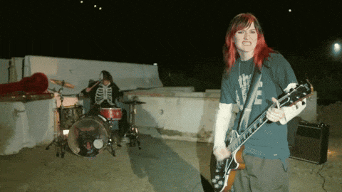 a woman playing a guitar in front of a drum set