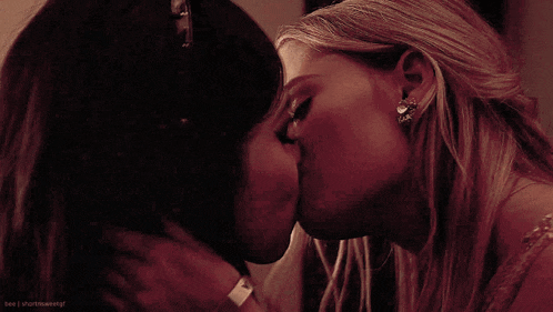 two women are kissing in a dark room with the words bee i shutitself visible in the corner