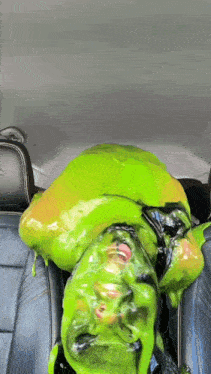 a person covered in green slime is laying in a car seat