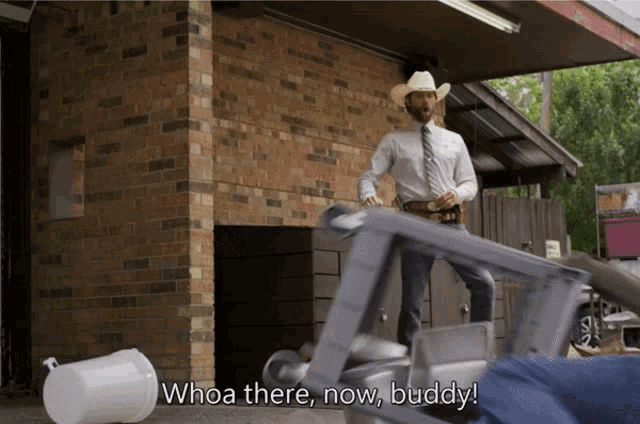 a man in a cowboy hat is standing next to a treadmill and says whoa there now buddy