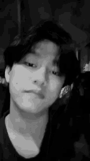 it is a black and white photo of a young man making a funny face .