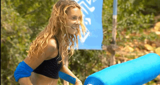 a woman in a bikini stands in front of a blue flag that says ' nc ' on it