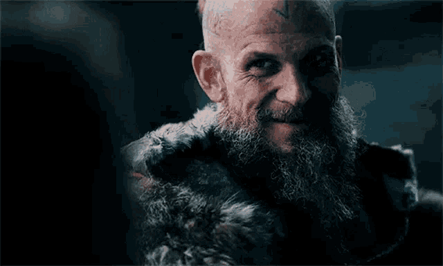 a man with a beard and a tattoo on his head is smiling .