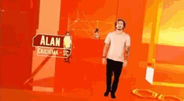 a man is walking in a room with a sign that says alan on it .