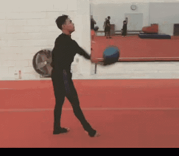a man in a black shirt is throwing a blue ball