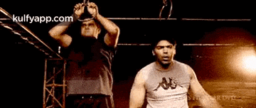 two men are standing next to each other in a wrestling ring .