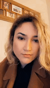 a close up of a woman 's face with a nose ring and a picture frame behind her .