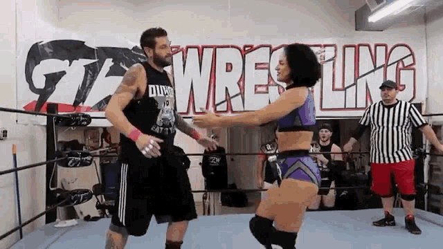 a man and a woman are wrestling in a wrestling ring in front of a banner that says wrestling