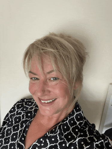 a woman wearing a black and white shirt is smiling for the camera