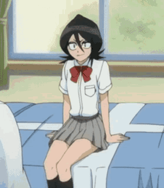 a girl in a school uniform sits on a bed with her legs crossed