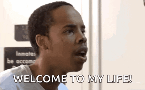 a man is saying welcome to my life in front of a door .