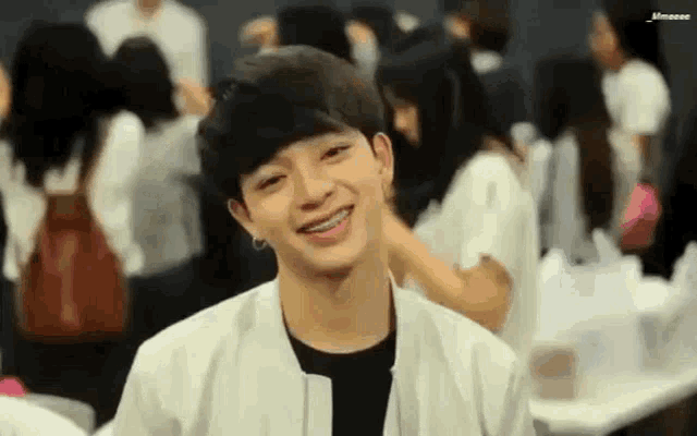 a young man with braces on his teeth is smiling in a crowd of people .