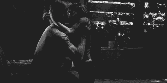 a black and white photo of a man and a woman hugging each other .