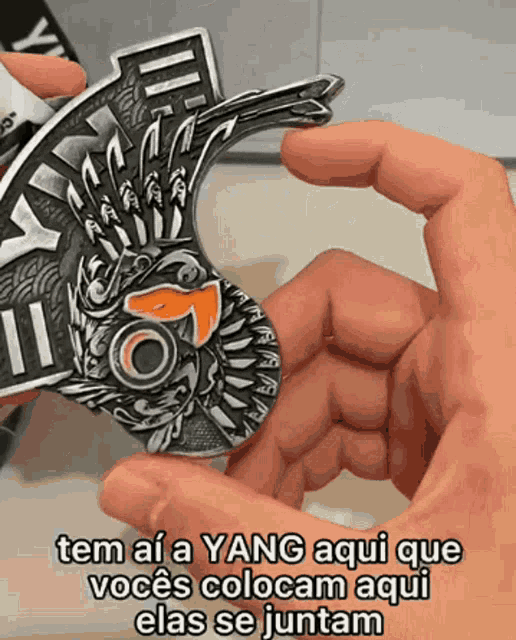 a person holding a coin that says " tem ai a yang aqui que voces colocam aqui elas se juntam "